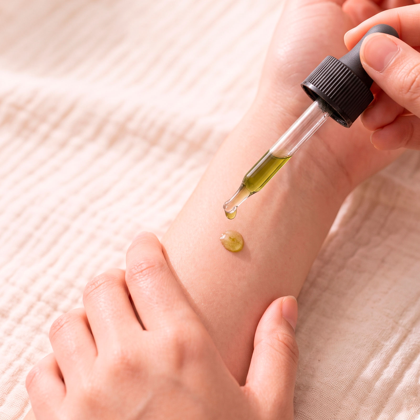 A close-up shot of a mother apply a single drop of Kawakawa Sensitive Oil to the arm of their child with sensitive skin.