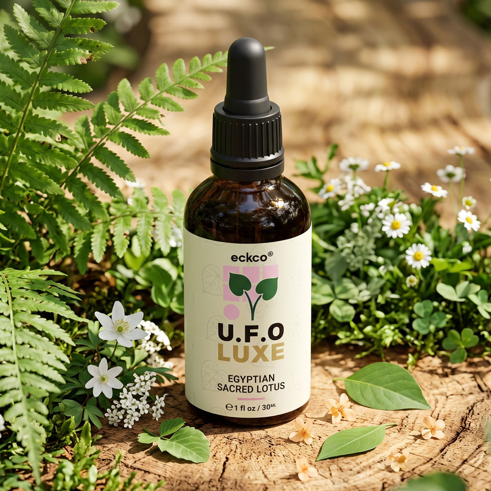 An amber glass dropper bottle of eckco U.F.O LUXE Egyptian Sacred Lotus serum resting on a wooden tree stump, surrounded by green ferns and small white flowers in warm sunlight